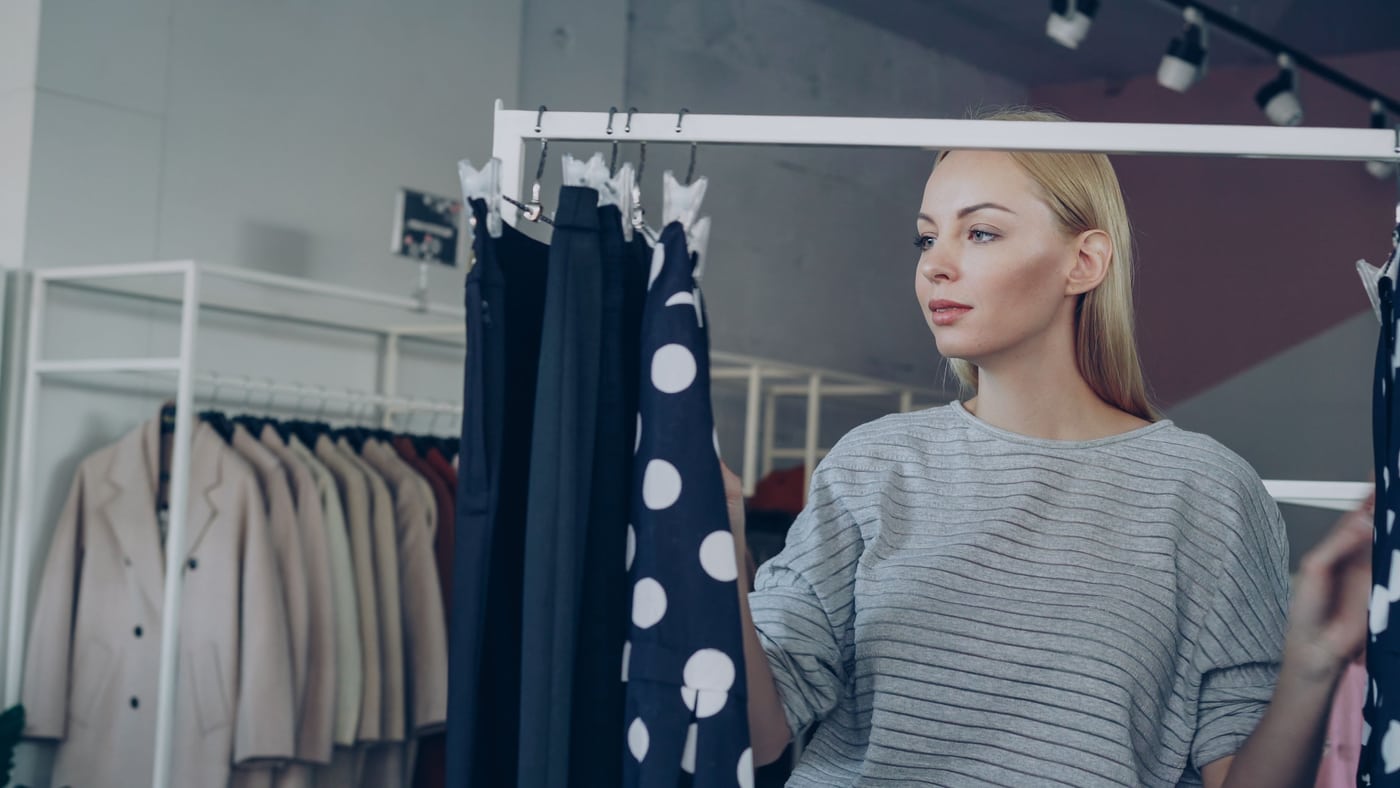 A customer browsing clothes on racks in a boutique.