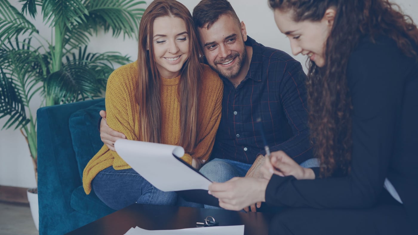 A couple reviewing documents with a financial adviser.